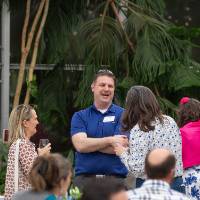 Adam Tate laughing while chatting with two female colleagues